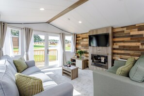 Un salon moderne avec un canapé, une table basse, un téléviseur fixé à un mur en bois et une cheminée.