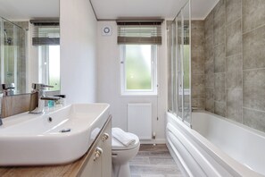 Een bad/douchecombinatie, handdoeken, toiletpapier