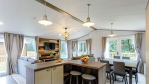 Een moderne keuken met een centraal eiland, barstoelen en een eethoek met een tafel en stoelen.