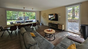 A modern living room with a large sofa, a dining area, and a TV.