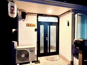 Ein Hotel Eingang mit einer schwarzen Tür, einer Fußmatte mit dem Aufdruck "HAPPY PLACE" und einem Schild darüber.