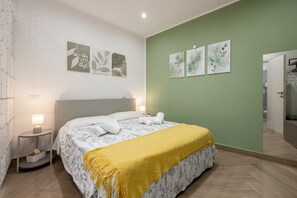 Quarto com cama, mesas de cabeceira, obras de arte nas paredes e espelho.