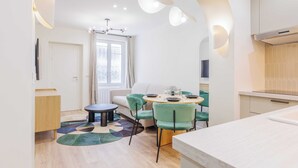 A modern kitchen with a white countertop, a dining area with a round table and chairs, and a window with curtains. - Cozy Apartment 2br/6p - Sacre-coeur / Montmartre (Paris)