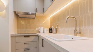 A modern kitchen with a white countertop, stainless steel sink, and a range hood. - Cozy Apartment 2br/6p - Sacre-coeur / Montmartre (Paris)