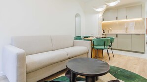 A modern living room with a sofa, a round coffee table, and a dining area with a table and chairs. - Cozy Apartment 2br/6p - Sacre-coeur / Montmartre (Paris)