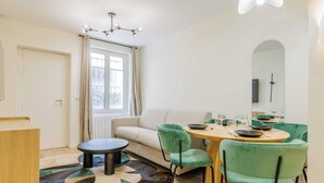 A modern living room with a sofa, round dining table, and green chairs. - Cozy Apartment 2br/6p - Sacre-coeur / Montmartre (Paris)
