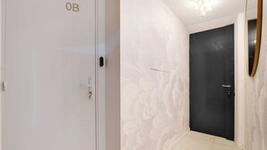 Un couloir avec une porte blanche portant l’inscription « OB » et une porte noire.