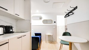 Une cuisine moderne équipée d’une machine à café, d’un canapé bleu, d’une petite table ronde et d’une chaise.