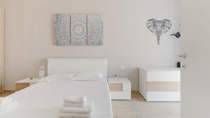 A modern bedroom with a bed, bedside tables, a nightstand, and a wall art piece. - GuestHost - Naviglio Grande Bright Apartment (Milan)