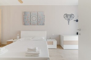 A modern bedroom with a bed, bedside tables, a nightstand, and a wall art piece.