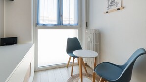 A modern room with a sliding glass door, two chairs, a small table, and a radiator. - GuestHost - Naviglio Grande Bright Apartment (Milan)