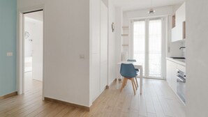 A modern kitchen with white cabinets, a blue chair, and a dining table. - GuestHost - Naviglio Grande Bright Apartment (Milan)