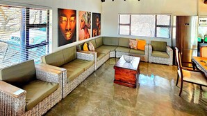 A spacious living area with a high thatched ceiling, wicker furniture, and artwork on the walls.