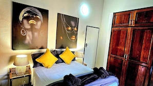 A bedroom with a bed, a nightstand, a lamp, a ceiling fan, and a wardrobe.