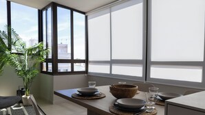 Eine moderne Küche mit einem großen Fenster, einem gedeckten Esstisch mit Tellern, Schüsseln und Gläsern sowie einem Blumentopf.