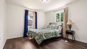 Una camera da letto con un letto, un comodino, una lampada e una finestra con tende.
