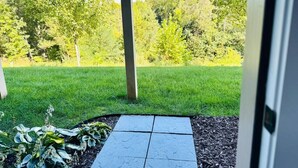 A pathway leading to a grassy area with trees and a clear sky.