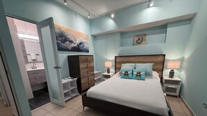 Ein Schlafzimmer mit Bett, zwei Nachttischlampen, einem Nachttisch, einem Kleiderschrank und einem durchgehenden Türbogen sichtbaren Badezimmer.