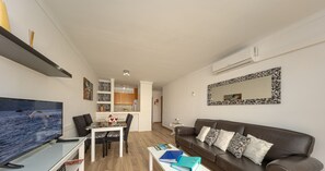 Un salon moderne doté d’un téléviseur à écran plat, d’un canapé, d’une table basse et d’un coin repas avec une table et des chaises.