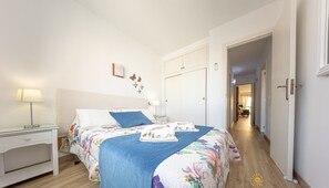 Une chambre à coucher comprenant un lit, une table de chevet, une armoire et un couloir menant à une autre pièce.