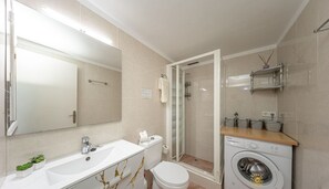 Un baño moderno con lavamanos, inodoro y ducha blancos.