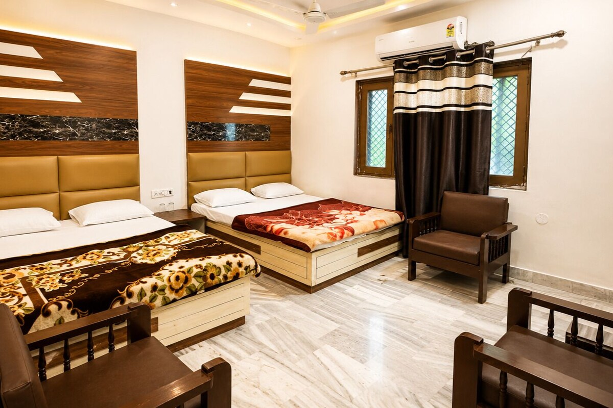 A hotel room with two beds, a sofa, a chair, and a window with curtains.