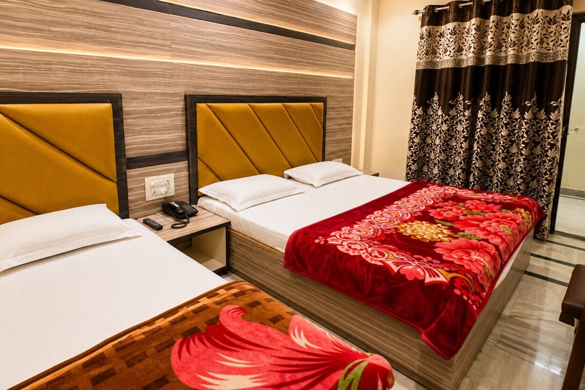 A hotel room with two beds, a nightstand with a phone, and a red floral bedspread.