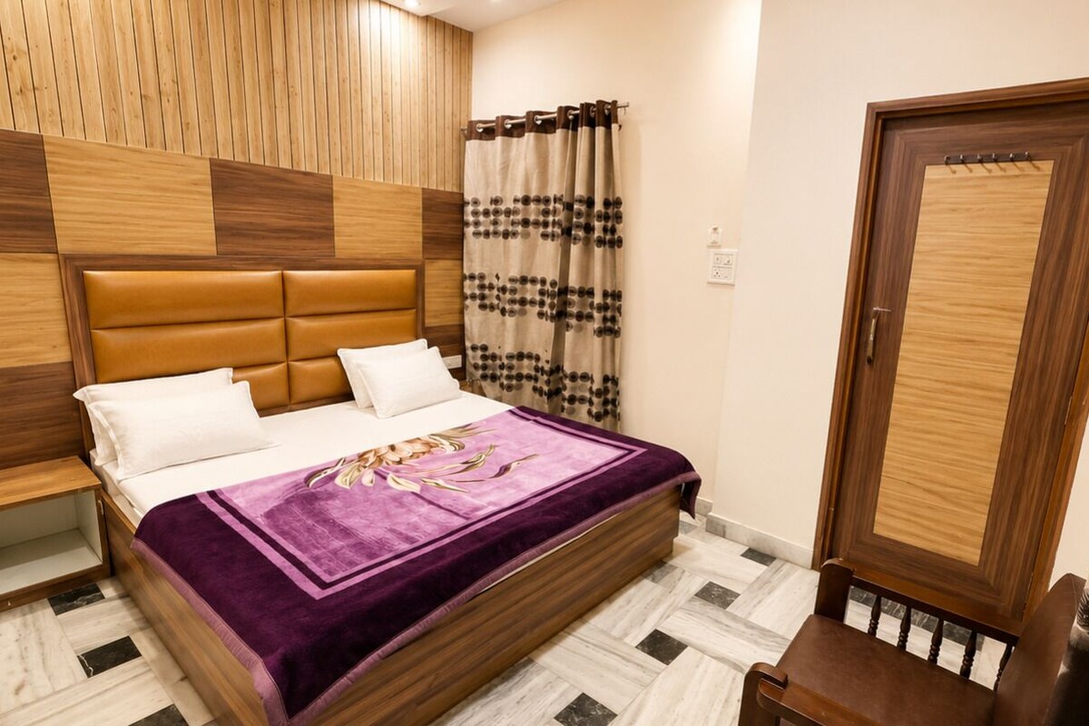 A bedroom with a bed, wooden headboard, a door, and a nightstand.