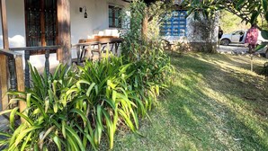 A traditional house with a tiled roof, a wooden porch, and a small garden area with green plants. - w Peaceful 1BR Surrounded by Nature in Huaraz (Yungar)
