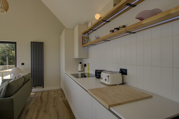 A modern kitchen with white cabinets, a wooden countertop, and a built-in oven.