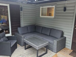 A corner seating area with a grey sofa, two wicker chairs, and a small table. - 4 Star Holiday Home in By Kyrkby (By Kyrkby)