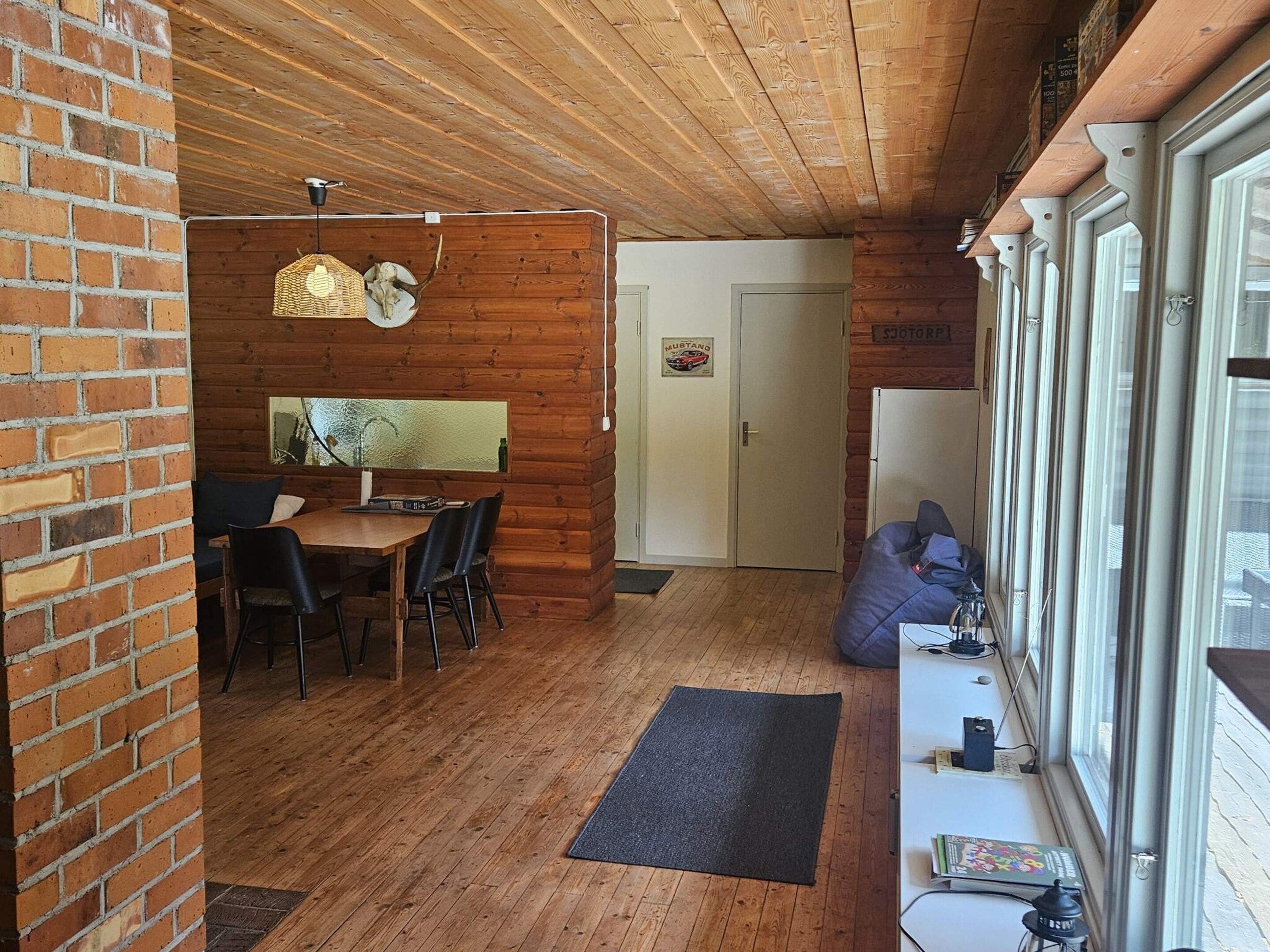 Interior de madera con zona de comedor, una puerta con un letrero de 'Mustang' y una ventana con persianas.
