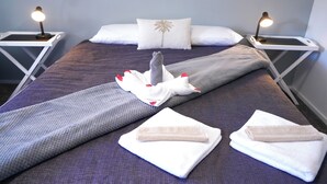 A neatly made bed with a towel centerpiece, white pillows, and bedside lamps. - ACCOMMODATION GATEWAY MOTEL (Palmerston North)