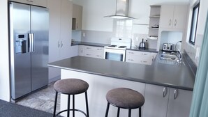 A modern kitchen with stainless steel appliances, a central island with stools, and ample counter space. - ACCOMMODATION GATEWAY MOTEL (Palmerston North)
