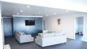 A modern living room with a large flat-screen TV, two sofas, and a coffee table. - ACCOMMODATION GATEWAY MOTEL (Palmerston North)