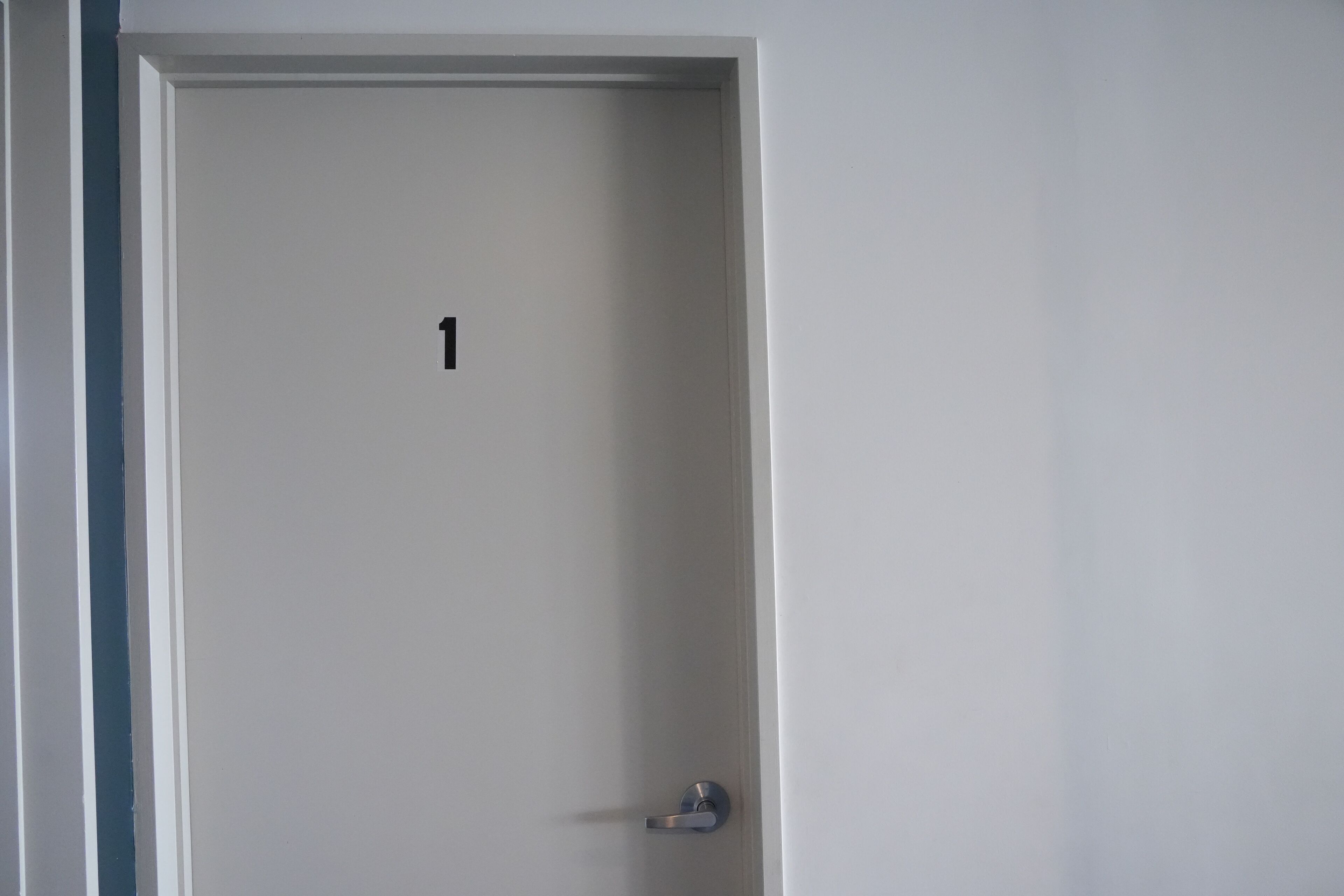 A closed door with a number '1' on it, a metallic handle, and a white wall.