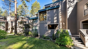 Une maison moderne à deux étages, dotée d’une pelouse bien entretenue et de quelques arbres.