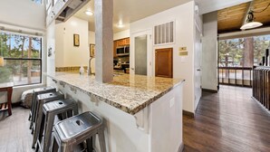 A kitchen with granite countertops, stainless steel appliances, and a bar area with stools.
