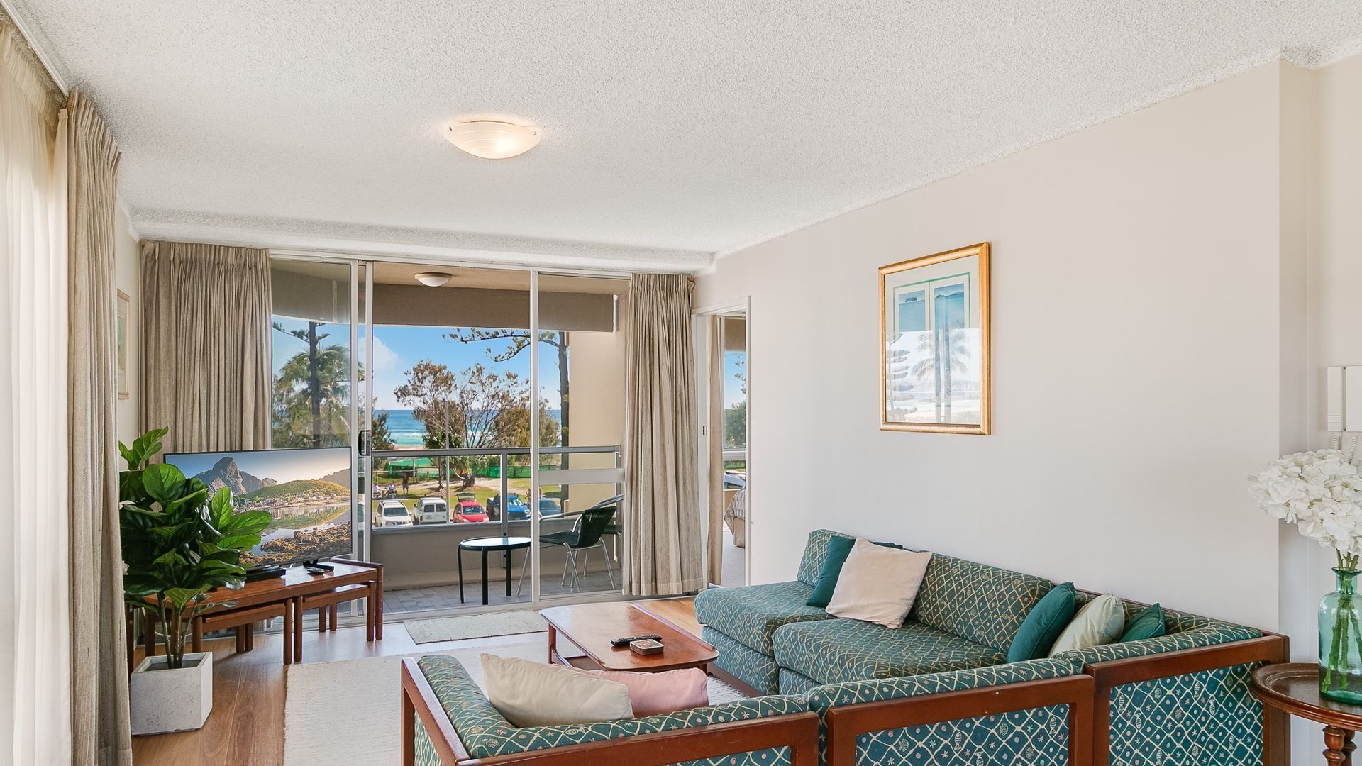 A spacious living room with a balcony, a dining area, and a view of the ocean.