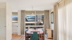 Un comedor con una mesa redonda y sillas, vistas de edificios y una estantería.