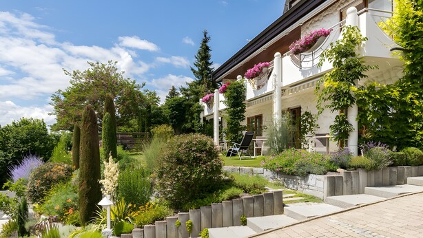 Ein Gebäude mit Garten, Stufen zum Eingang und blauem Himmel.