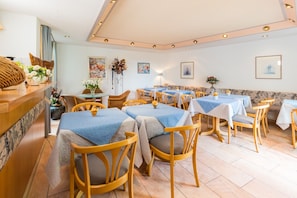 A restaurant with multiple tables and chairs, a reception area, and artwork on the walls. - Room 'Doppelzimmer 7' with Mountain View, Private Terrace and Wi-Fi (Gailingen am Hochrhein)