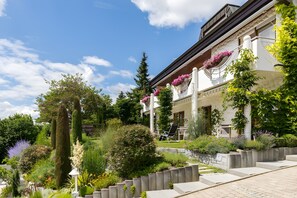 Un bâtiment doté d’un jardin, avec des marches menant à l’entrée, et un ciel dégagé.