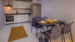 A compact kitchen with white cabinets, a stainless steel refrigerator, and a dining area with a table set for two.