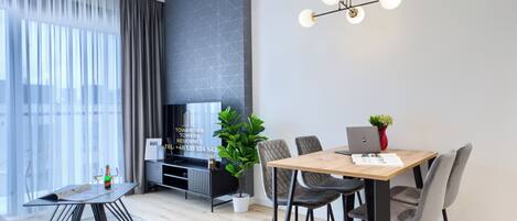 Una sala de estar moderna con comedor, televisor y planta.