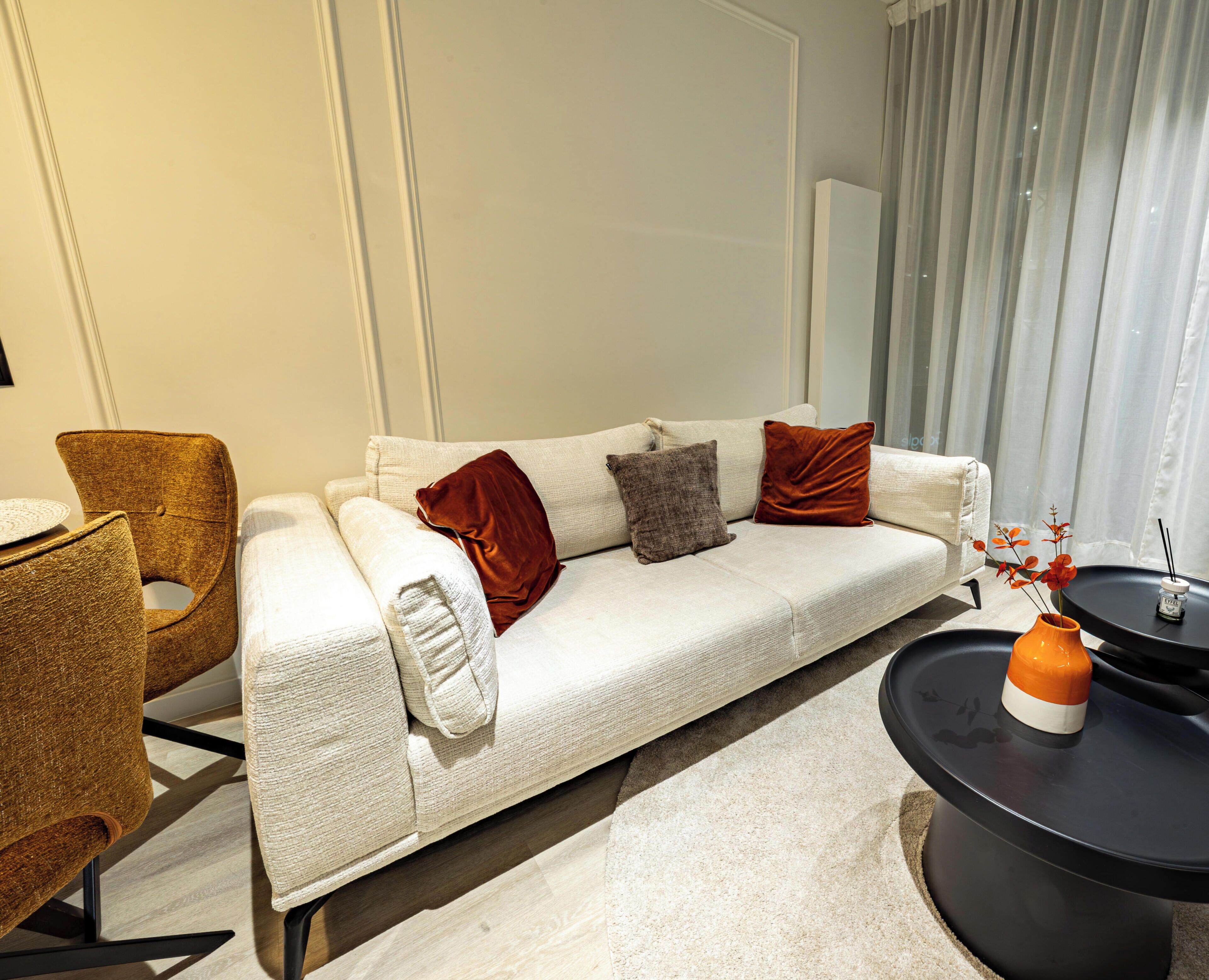 A modern living room with a sofa, a chair, a coffee table, and a vase with flowers.