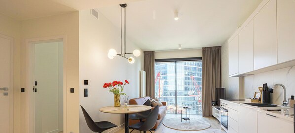 Eine moderne Küche mit Essbereich, ein großes Fenster mit Blick auf ein Gebäude und eine Vase mit Blumen auf dem Tisch.
