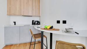 A modern kitchen with a white countertop, wooden cabinets, and a round dining table with chairs. - Beautiful Cozy Apartment - 1 Bdr/4p - Gare de Lyon / AC (Paris)
