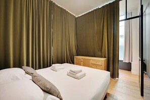 Ein Hotelzimmer mit einem Bett, einem Holzschrank und Vorhängen.