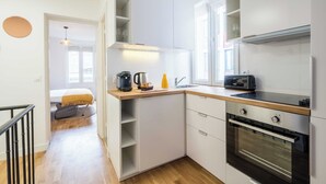 Une cuisine moderne avec des armoires blanches, un four encastré et une machine à café posée sur le plan de travail.